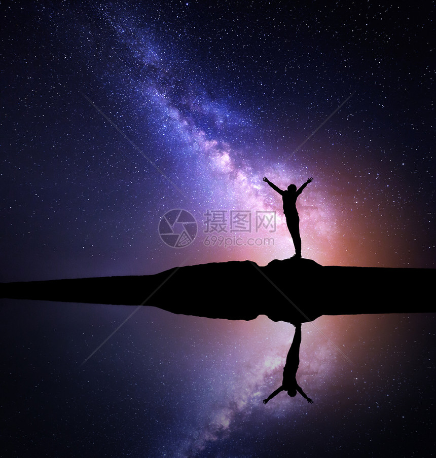 银河系山上个站立的女人的轮廓银河系夜空个站着的女人的轮廓,她举手臂,站湖边的山上,倒影水中紫色银河女图片