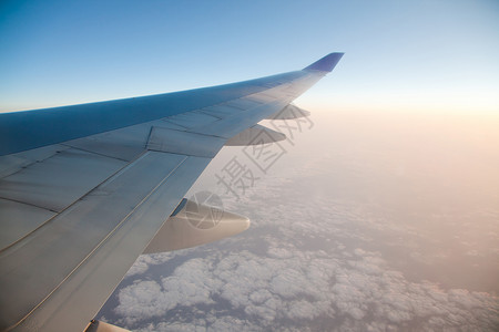 日出与飞机翅膀它的窗户与云景图片
