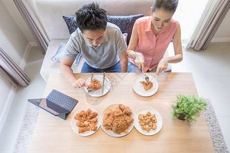 轻的亚洲夫妇吃炸鸡房子的客厅里吃炸鸡,以现代生活方式的为最高观图片