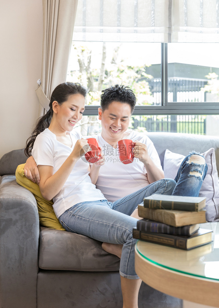 轻的亚洲夫妇当代房子的客厅里喝咖啡,以适应现代生活方式的图片