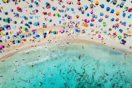 牙列拥挤阳光明媚的早晨,用五颜六色的雨伞俯瞰沙滩,用透明的蓝色水海湾游泳西牙巴利阿里群岛马略卡岛旅行的风景景观背景