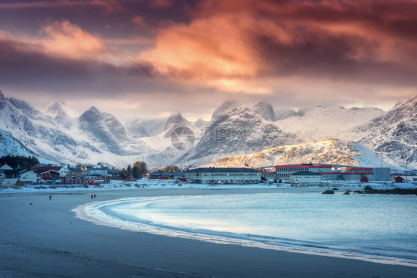 美丽的北极沙滩,冬季挪威洛福滕群岛日落时蓝色的大海风景雪山,天空橙色的云,水,村庄建筑,步行的人自然图片