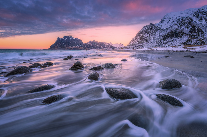 美丽的沙滩上模糊的水中的石头,五颜六色的多云粉红色的天空日落时的雪山犹他州海滩,洛芬岛,挪威冬季景观与海洋,波浪,岩图片