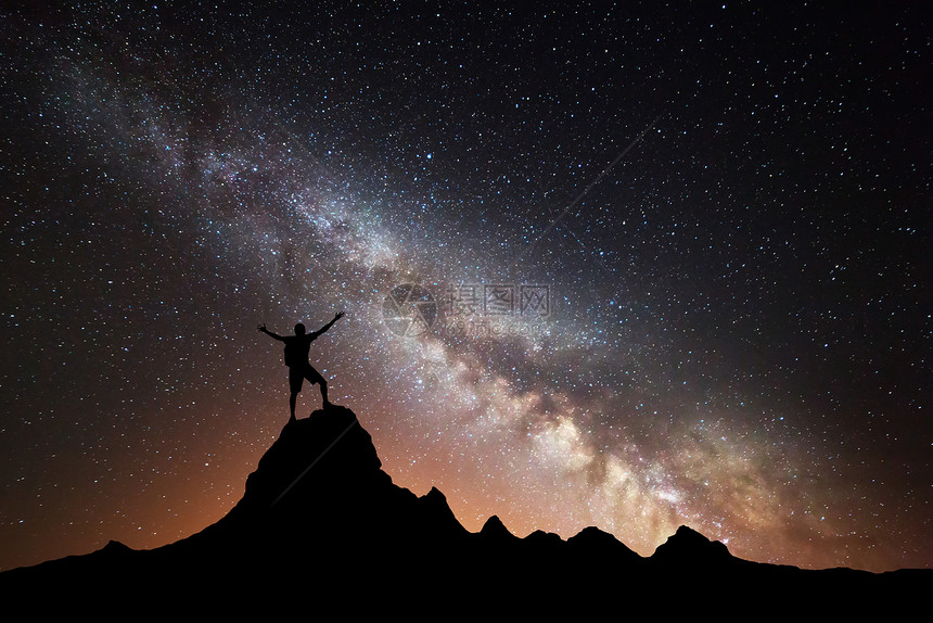 银河系的景观五颜六色的夜空,星星个快乐运动的人的轮廓,举手臂山顶上高岩石背景与星系个人的轮廓图片