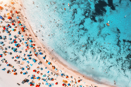 牙列拥挤空中观看沙滩与彩色雨伞,游泳的人海湾与透明的蓝色水日落夏天西牙巴利阿里群岛马略卡岛旅行的风景景观背景