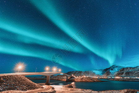 挪威洛福滕岛的桥上照明的北极光北极光极地灯光的星空夜间冬季景观与极光,道路,村庄雪山旅行背景图片
