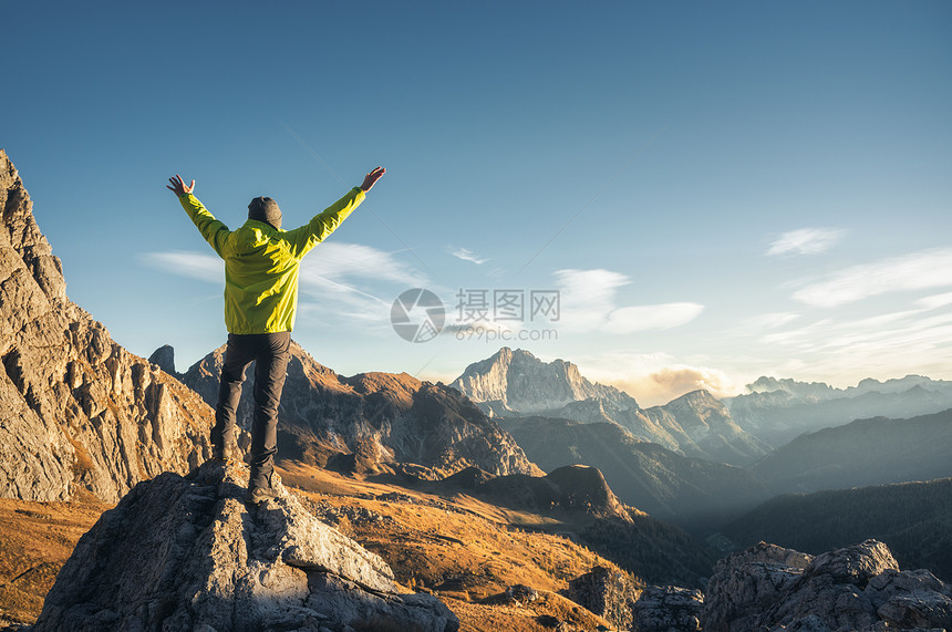 运动的人站石头上,举手臂日落时抗山谷快乐的轻人,岩石,秋天的森林蓝天白云石,意大利旅行者高山上徒步旅行图片