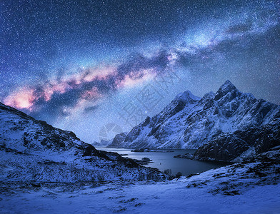 雪上明亮的银河覆盖着挪威冬天的山脉海湾壮观的景观与雪岩,星空,五颜六色的星系,美丽的峡湾洛芬岛背景图片