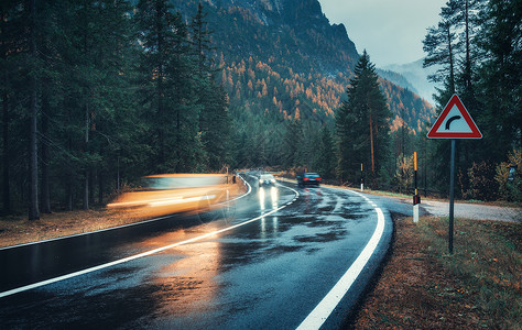 空山新雨秋天的森林里,道路上模糊的汽车雨中运动阴雨天完美的沥青山路巷道,意大利阿尔卑斯山的松树运输雾林中的公路旅背景