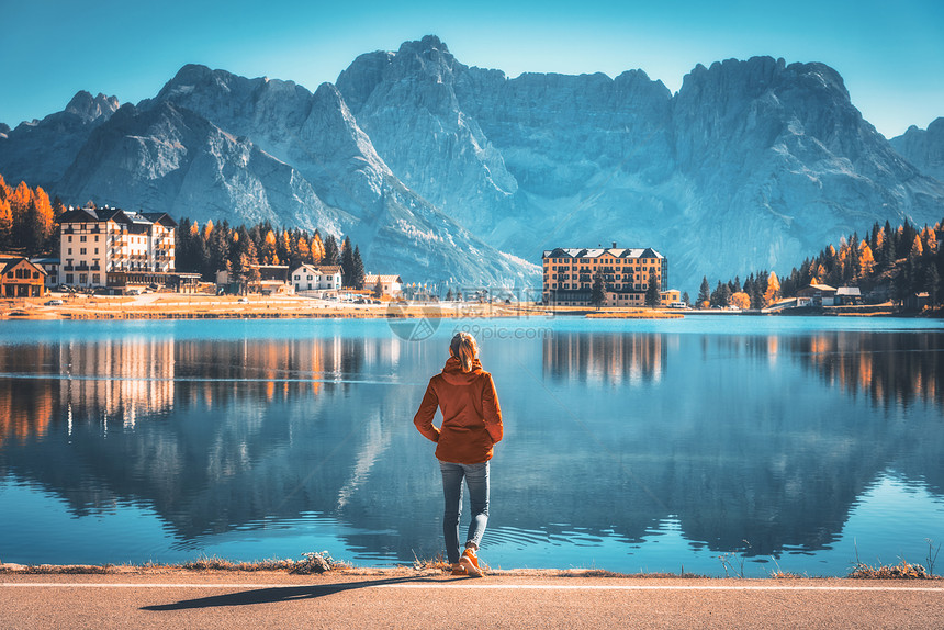 秋天日出时,站米苏丽娜湖海岸的轻女子意大利白云石风景与女孩穿着红色夹克,倒影水,建筑物,蓝天意大利阿尔卑斯山图片