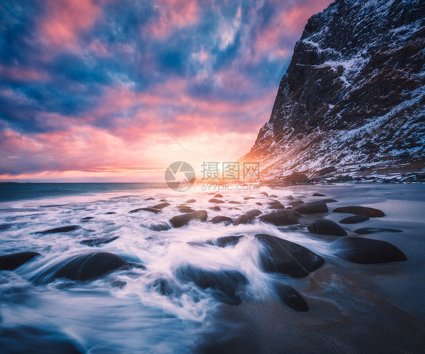 沙滩上模糊的水中的石头,蓝天上粉红色的云,日落时雪山犹他州海滩,洛芬岛,挪威冬季景观与海洋,波浪,岩石晚上图片