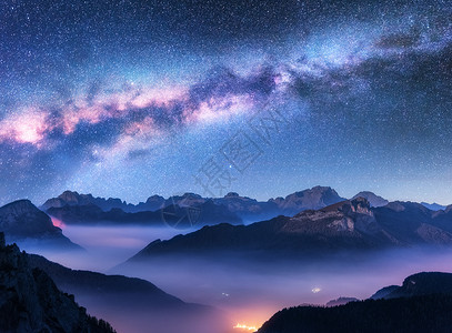 多彩星空光效秋天的夜晚,雾中的银河山上景观与高山山谷,低云,紫色星空与银河,城市照明空中飞行帕索Giau,白云石,意大利背景