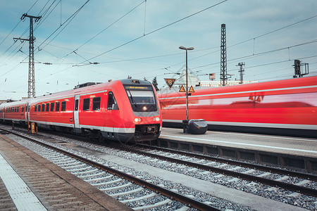 德国纽伦堡日落时配现代红色客运列车的火车站带复古色调的铁路工业景观图片