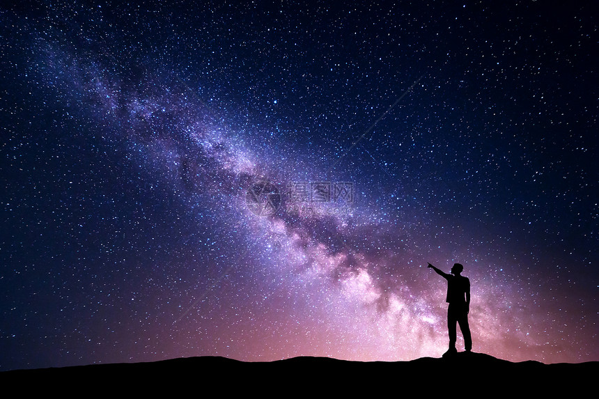 银河,个站立的轻人的轮廓,指着山上夜空中的夜空夜风景美丽的宇宙,紫色的天空充满了星星光图片