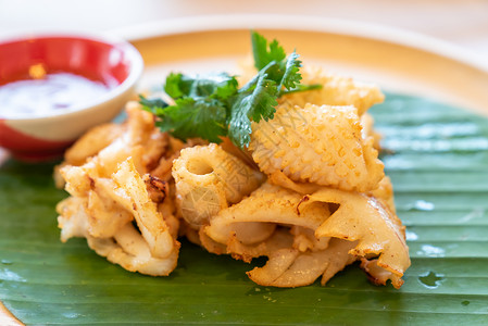 烤鱿鱼,泰国街头海鲜美食香蕉叶木桌上背景图片