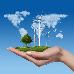 草地上树的风力涡轮机握着女人的手,抗蓝天由云成的世界全球绿色能源风力涡轮机,女手中树背景图片