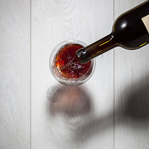 红酒白木桌上的瓶子里倒入璃杯的风景红酒瓶子里倒进璃杯里图片