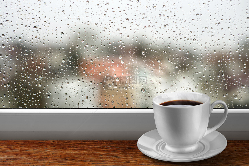 咖啡杯靠窗户上,雨天的景色图片