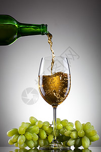 白葡萄酒用绿色葡萄瓶子里倒入璃杯图片