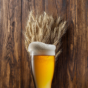 木制背景上小麦的杯啤酒图片