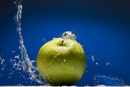 绿色苹果,蓝色背景上水溅图片