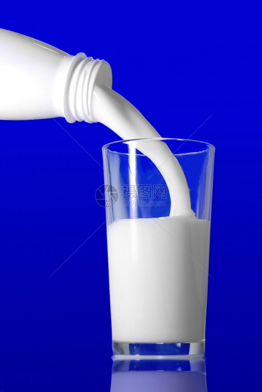 牛奶瓶子里倒进蓝色背景的璃里图片