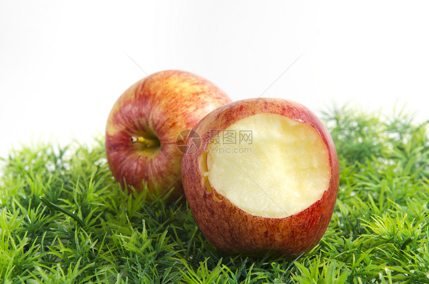部分被咬的苹果躺绿色的草地上图片