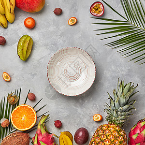 收集同的多色成熟热带水果,空盘子棕榈叶灰色混凝土桌子上图片