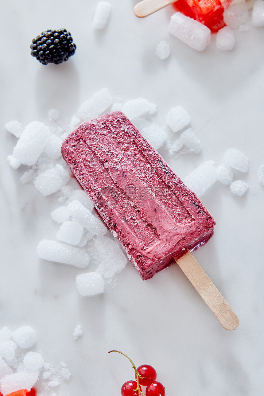 自制冰棒蓝莓奶油碎冰上的大理石背景与浆果,顶部视图夏天的浆果黑色醋栗冰淇淋冰棒碎冰上的大理石背景与浆果,顶部的图片