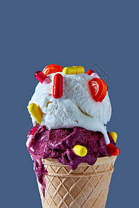 华夫饼锥与球浆果香草冰淇淋与红色黄色胶囊棒棒糖蓝色背景下的特写夏季卡他疾病的及其治疗冷美味的冰淇淋华夫饼背景图片
