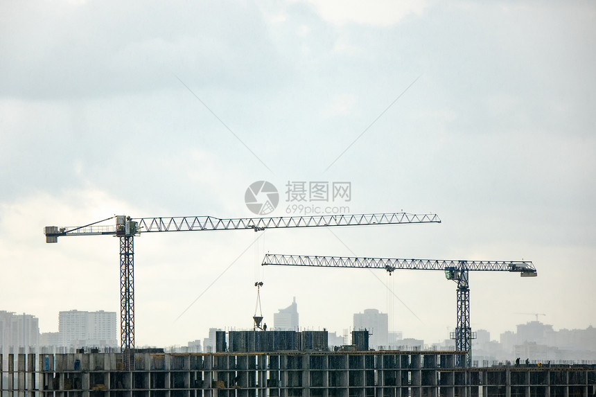 建筑正建造中,两台塔式重机抗灰色多云的天空来自无人机的照片工业景观与重机的轮廓灰色多云的背景图片