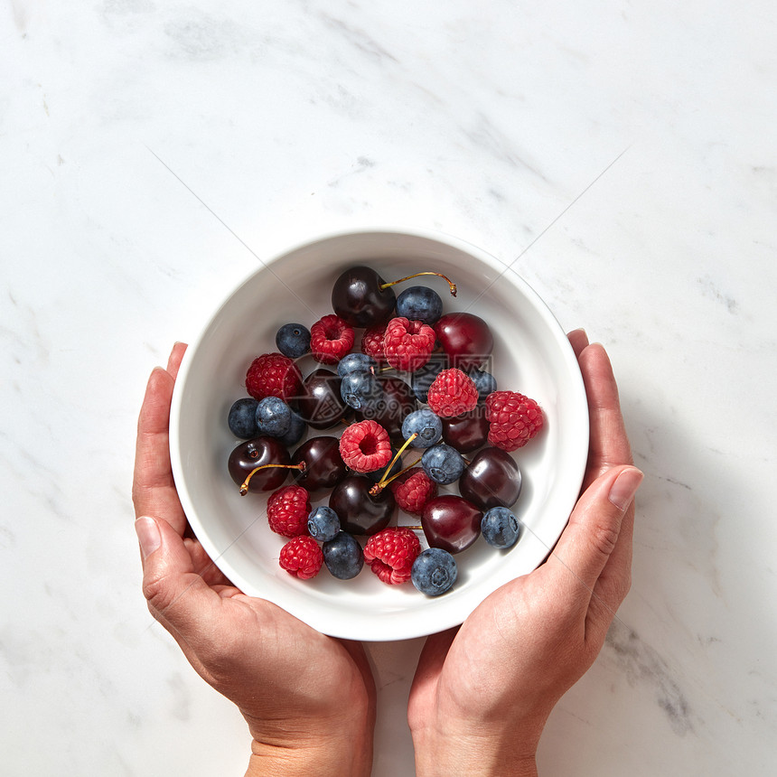 天然机水果,浆果盘子里的灰色石头背景的健康食品的平躺女人的手着个盘子,成熟的甜浆果樱桃图片