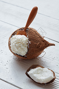 新鲜的碗椰子冰淇淋,用木勺轻木背景上美味的香草冰淇淋椰子里图片