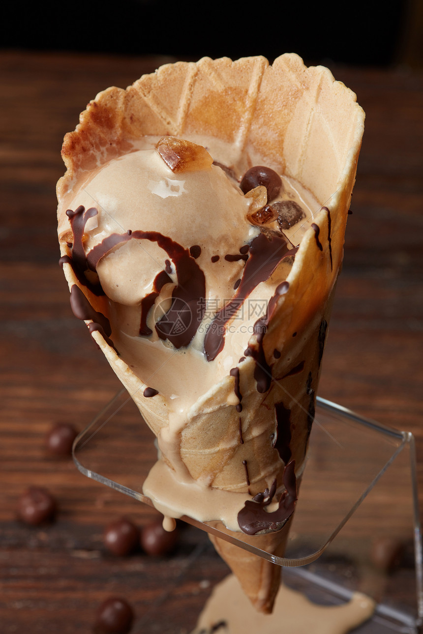 融化冰淇淋与巧克力顶部华夫饼锥个木棕色背景的立场华夫饼锥冰淇淋图片