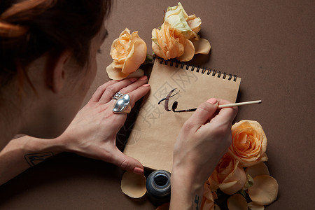 侧看女人开始工艺纸上写爱字用玫瑰写情书图片
