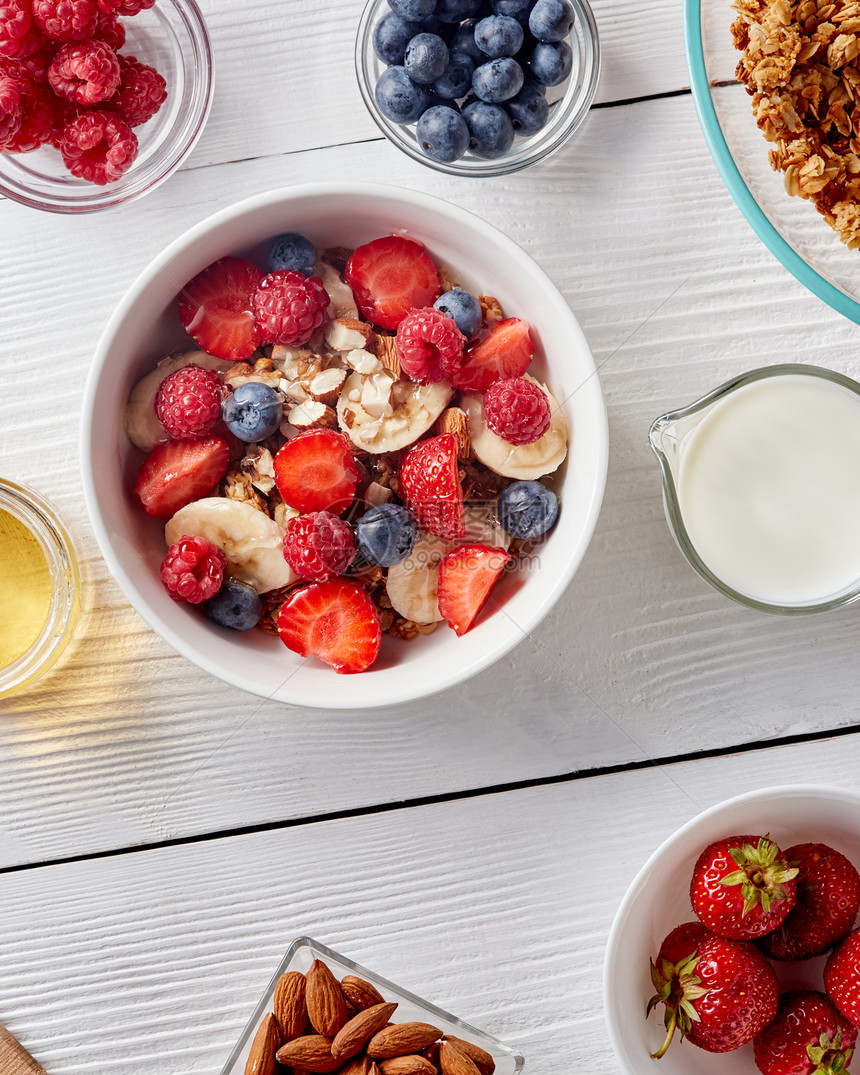 健康的机早餐,来自天然冰淇淋,草莓,蓝莓,牛奶,杏仁,花蜜天然健康排食品的顶部视图白色陶瓷碗与天然机浆果,水图片