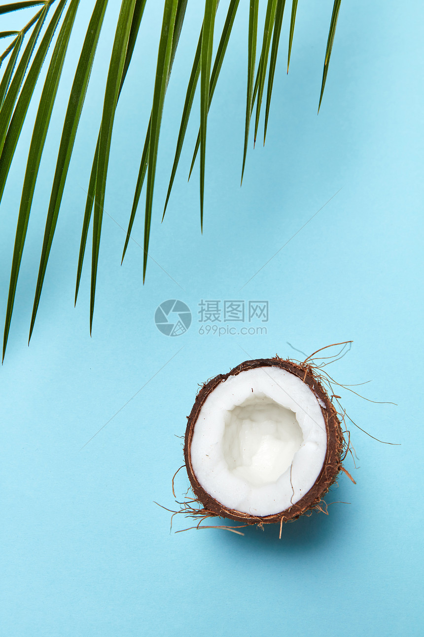 个新鲜的半机椰子个棕榈叶个蓝色的背景与的天然化妆品的成分的风景种绿色的棕榈叶,半椰子图片