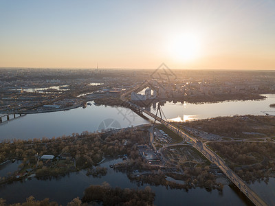巴顿鸟瞰桥道路上的DNEPR河上的个绿色岛屿河中央基辅市日落,乌克兰日落时基辅市的鸟瞰聂伯河上的北桥背景