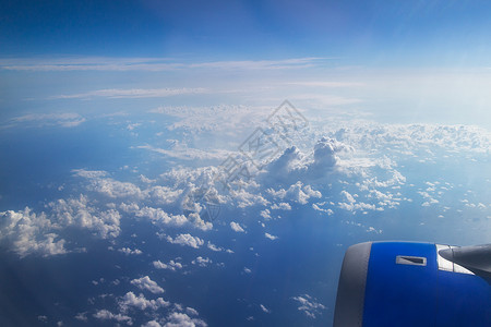 透过飞机的窗户看的云天空,飞机的机翼飞越蓝天多云的天空图片