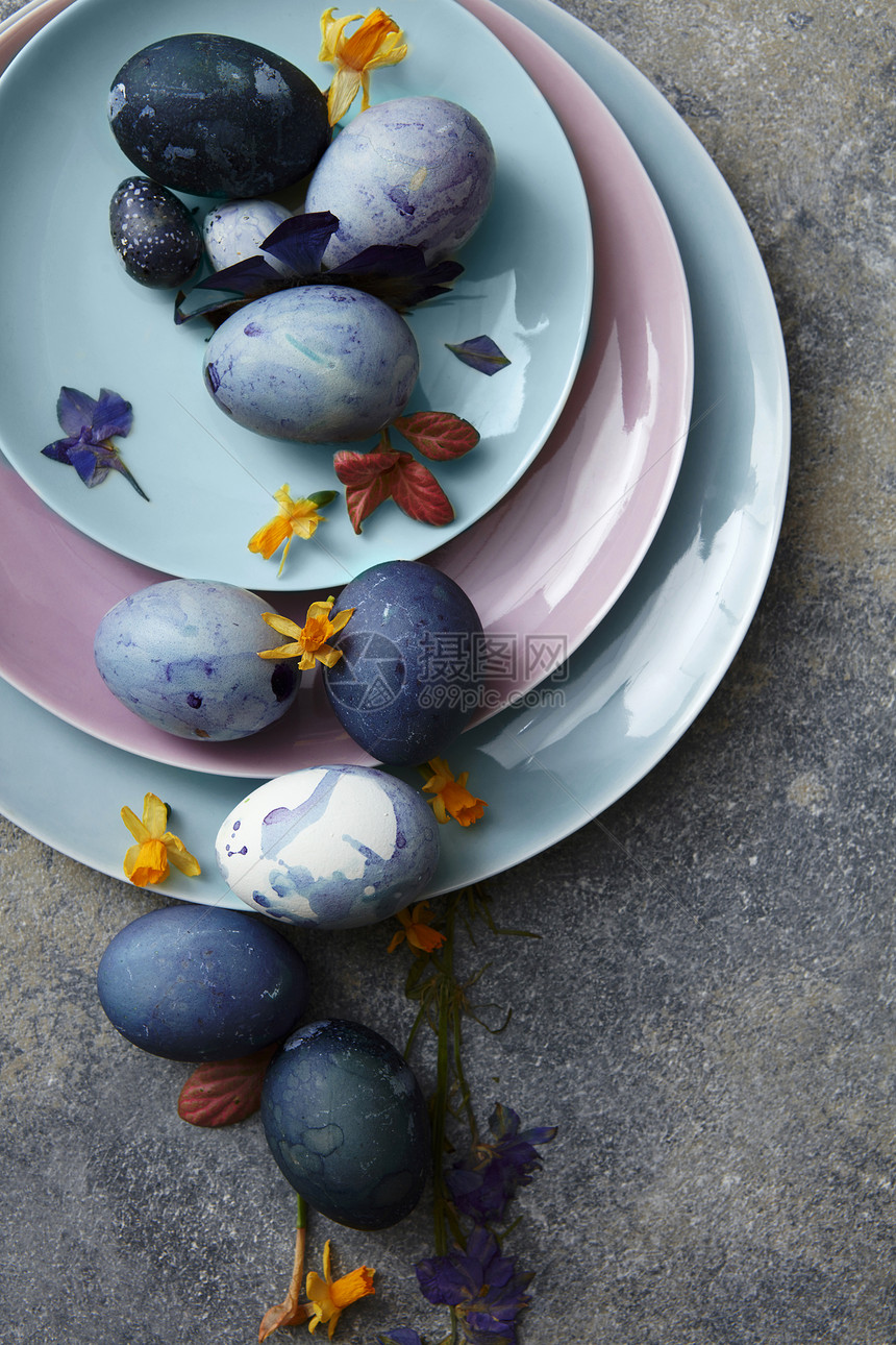 三盘同大小的复活节鸡蛋花瓣石头背景上蓝色复活节彩蛋图片