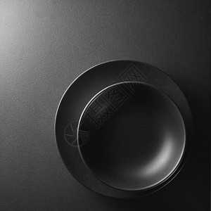 两个黑色的盘子角落的黑色背景上背景上的黑色盘子图片
