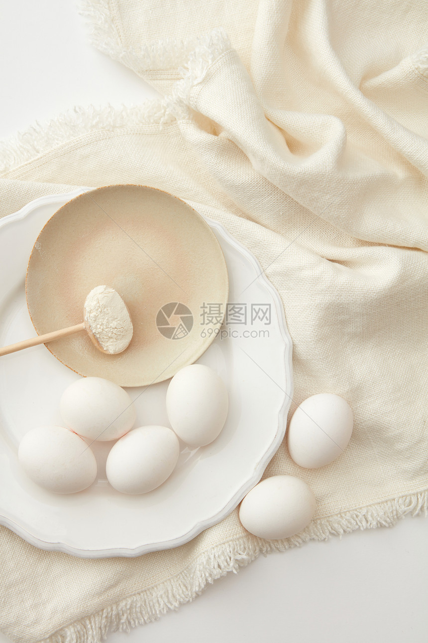 新鲜鸡蛋与粉米色餐巾上的白色背景粉加鸡蛋图片