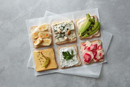 同类型的包与奶酪,蔬菜羊皮纸上的混凝土灰色背景同类型的吐司图片