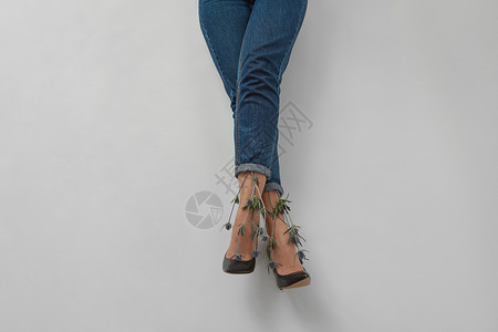 花艾琳尼格,女人的腿穿蓝色牛仔裤,灰色背景,女人的腿穿蓝色裤子,灰色图片