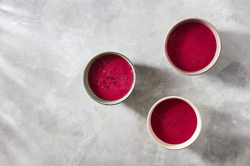 陶瓷手工碗与用的红色冰沙早餐混凝土背景与阴影的文字,平躺健康早餐素食者的三碗红色甜菜冰沙混凝土背景上,图片