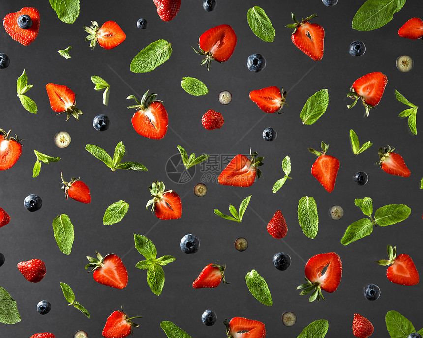 黑色背景上分离出草莓红熟蓝莓绿色薄荷枝的彩色成分的顶部视图平躺的水果图案与草莓,蓝莓薄荷叶黑色的背景图片