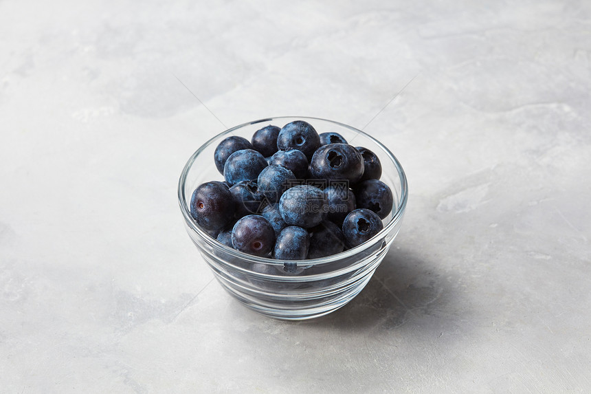 新鲜机蓝莓透明璃碗上的石光背景与蓝莓灰色的石头背景上个小璃碗图片
