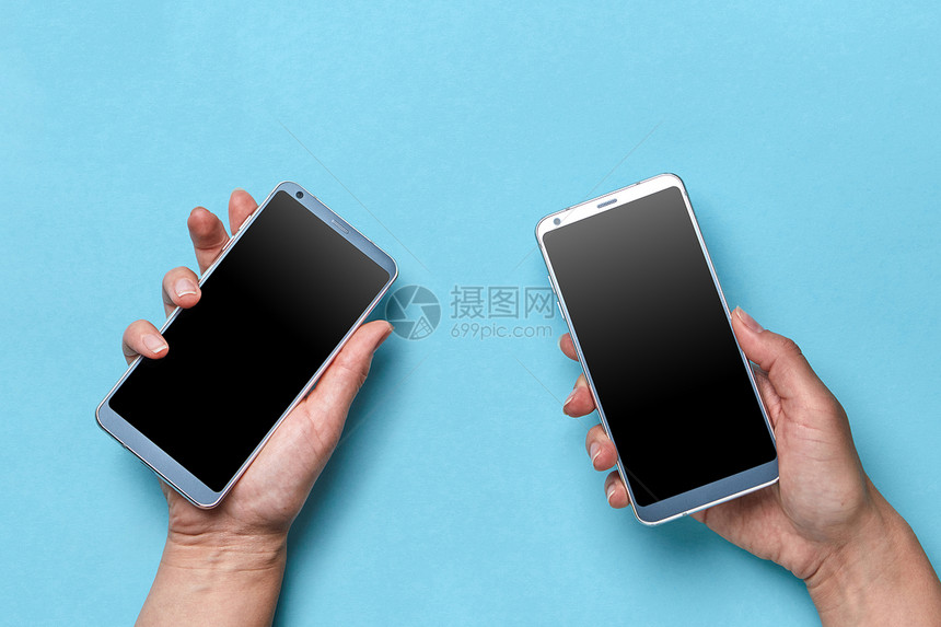 女孩男人的手着蓝色背景上的现代手机,文字的平躺男人女人的手着蓝色背景上的手机,文字的现代技术图片