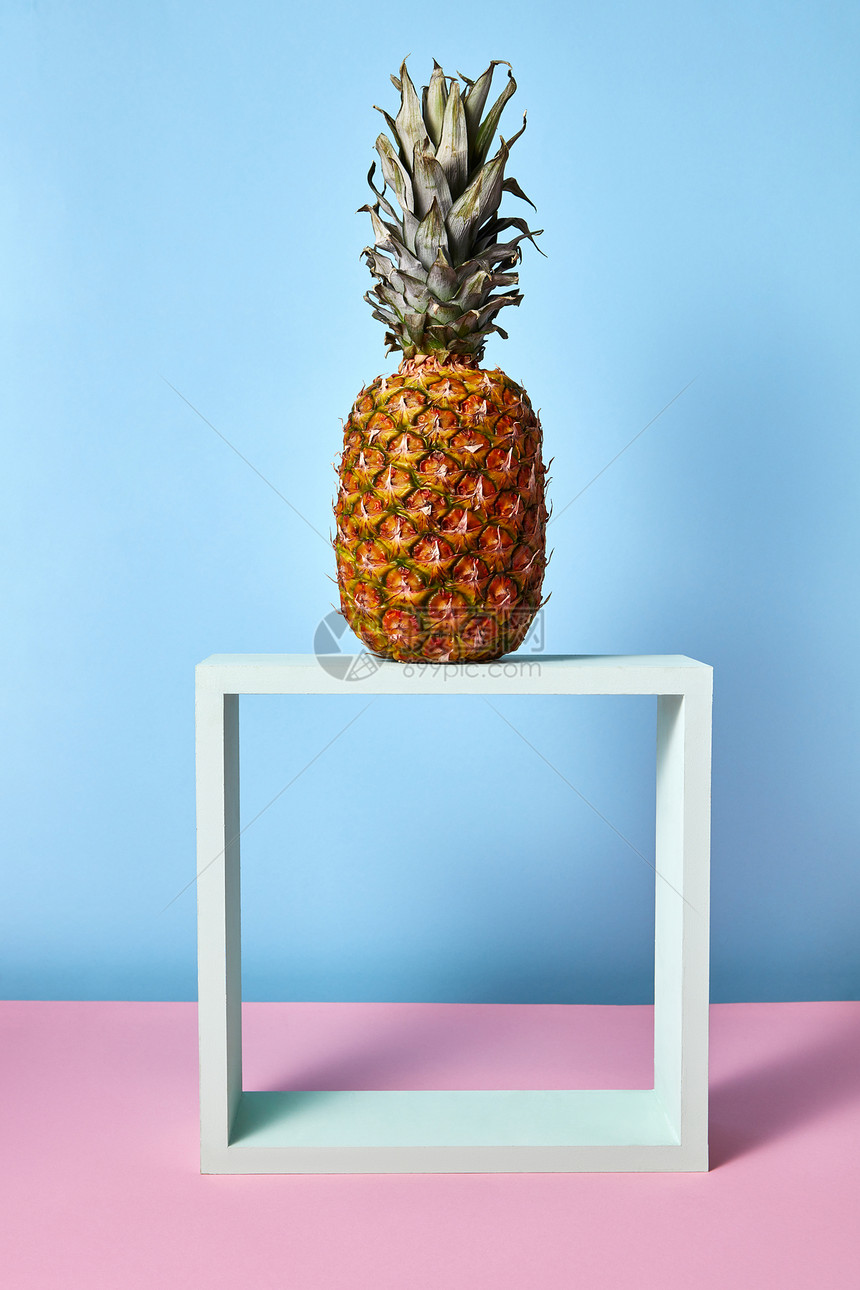 菠萝个木制的白色框架上的蓝色粉红色背景与食物菠萝图片