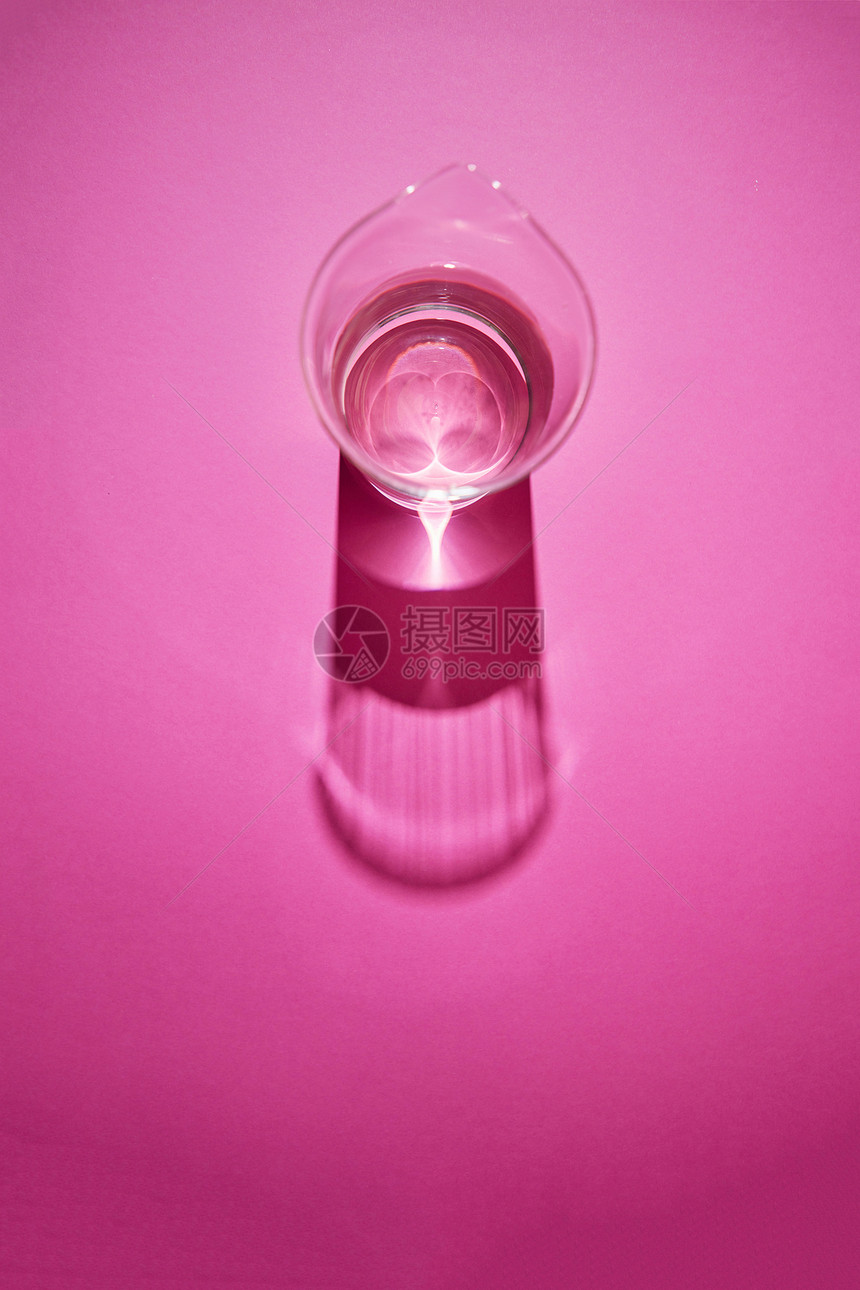 长阴影反射水璃上的粉红色背景与顶部视图干净的璃与水粉红色的纸背景与阴影图片